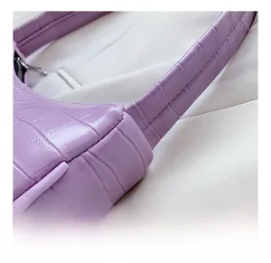 Détails de la texture crocodile violette et des coutures de la bandoulière sur le sac