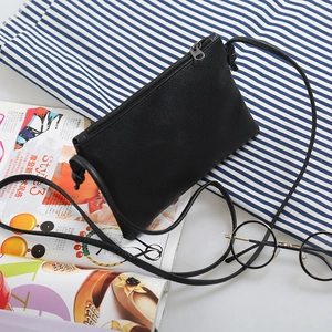 Minimalist black pebble leather crossbody bag with silver zipper on stylish lifestyle backdrop