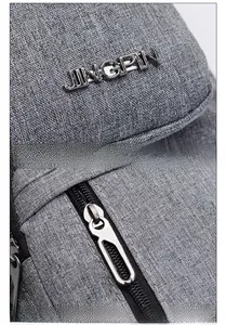 Detail of gray oxford fabric bag showing the metal JINGPIN logo and durable zipper