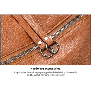 Detail of silver metal hardware rings and smooth zipper on brown washed PU leather bag
