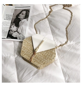 Detail of a woven crossbody bag with white leather flap, metal chain, and tassel accents