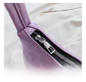 Détail de la fermeture éclair en métal argenté sur un sac violet à motif crocodile