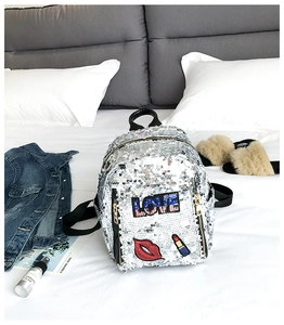 Detailed close-up of a silver sequin backpack featuring a red lip and LOVE embroidery