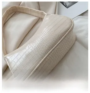 Gros plan du design arrondi et de la texture crocodile du sac baguette beige chic