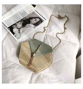 Detail view of hexagonal straw bag with green leather flap, gold tassels and chain strap