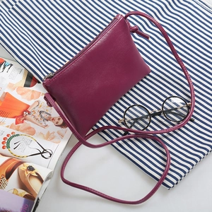 Minimalist wine red crossbody bag in synthetic leather shown on a styled flat lay background