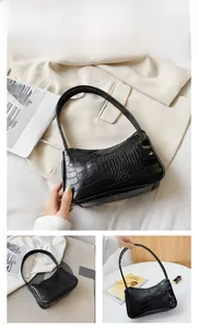 Vue détaillée du sac hobo noir à motif crocodile sur un blazer blanc élégant