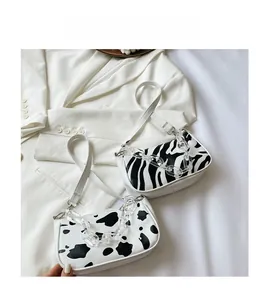 Flat lay of cow and zebra print baguette bags with acrylic chains on a white blazer