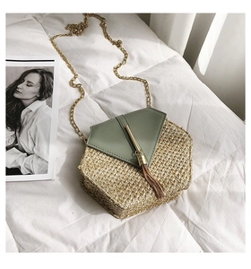 Detail of hexagonal straw crossbody bag with tassel charm and golden chain strap