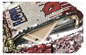 Detail view of sparkly sequin bag featuring a red lip motif and gold metal zipper