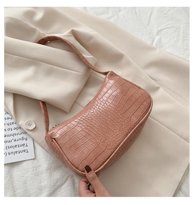 Détail du sac baguette rose élégant avec texture de crocodile et fermeture éclair
