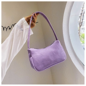 Détail du sac baguette violet avec motif crocodile gaufré et sa bandoulière élégante
