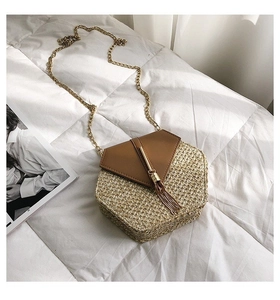 Detailed macro view of a hexagonal woven straw crossbody bag with golden tassel and chain