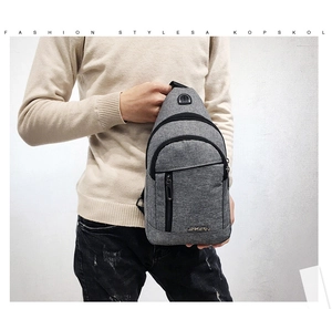 Detail of grey fabric crossbody bag featuring multiple zipper pockets and earphone port