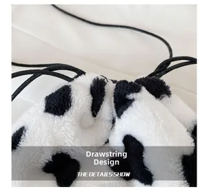 Close-up of plush cow print bag featuring black drawstring closure and soft texture