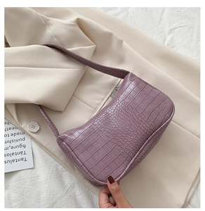 Vue détaillée de la texture crocodile violette et de la fermeture éclair du sac baguette chic