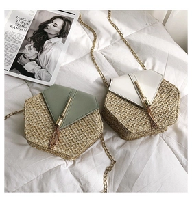 Detail of hexagonal straw crossbody bags with green and white leather flaps and gold tassels