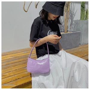Détail du sac à bandoulière violet clair à motif crocodile sur un mannequin