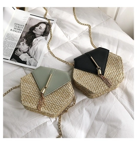 Flat lay of hexagonal straw crossbody bags with leather flap and tassel in black and green