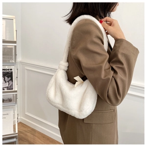 Détail d'un sac à épaule en fausse fourrure blanche porté par un mannequin en intérieur