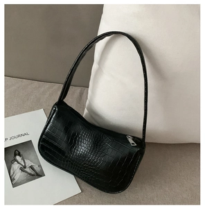 Détail du motif crocodile noir brillant sur le sac baguette rétro avec fermeture éclair argent