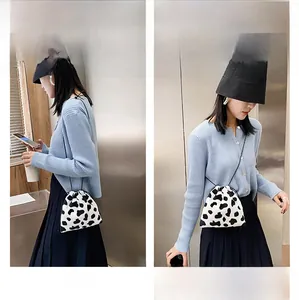 Detail view of cow print plush bucket bag showing shoulder and crossbody styling options