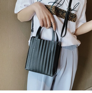 Détail d'un sac bandoulière plissé noir avec deux poignées et texture en similicuir chic