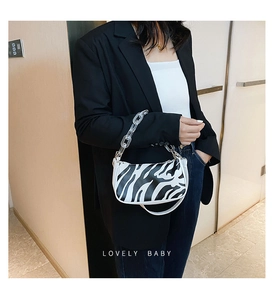 Detailed view of zebra print baguette bag featuring modern transparent acrylic chain link