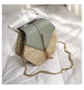 Detailed close-up of straw woven crossbody bag with green leather flap and gold tassel