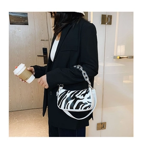 Detail of zebra pattern baguette bag featuring a transparent acrylic chain and white strap