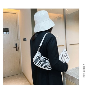 Detail of zebra pattern half-moon baguette bag with clear acrylic chain on model
