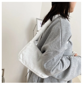 Detail shot of white faux fur underarm bag showing plush texture and shoulder strap