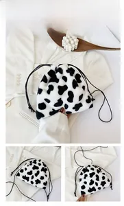Detail view of cow print plush drawstring bag with black strap and soft faux fur texture