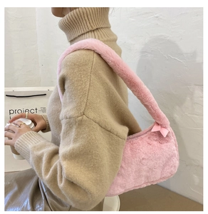 Detail view of pink plush shoulder bag with decorative bow and soft faux fur texture