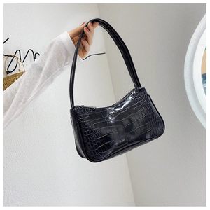 Détail de la texture brillante en relief crocodile noir sur un sac baguette classique