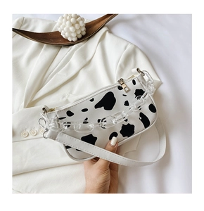 Close-up of cow print shoulder bag on white blazer with transparent acrylic chain detail