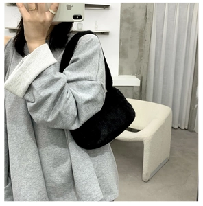Close-up of black faux fur shoulder bag worn with casual grey sweatshirt