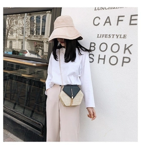 Detail of a chic hexagonal straw crossbody bag with black leather flap and gold chain
