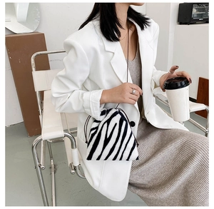 Detail of zebra pattern plush bucket bag with drawstring closure and slim shoulder strap