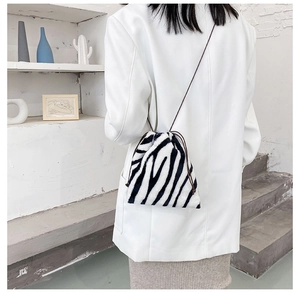 Detail of plush zebra print crossbody bag with drawstring closure on model