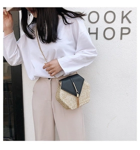 Detail of hexagonal straw crossbody bag with leather flap and golden tassel on model