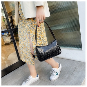 Mannequin portant un sac baguette noir motif crocodile avec un blazer blanc élégant