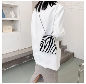Zebra print faux fur drawstring crossbody bag shown on a model in a minimal interior