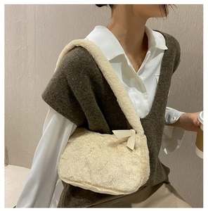 Detail of soft cream plush shoulder bag with decorative bow and high-density faux fur texture