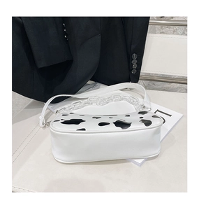 Detail of cow print baguette bag with white strap and acrylic decorative chain link