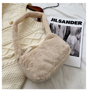 Close-up of a soft cream plush faux fur handbag on a stylish knitted background