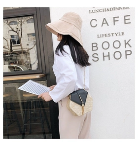 Detail of a hexagonal straw crossbody bag with gold chain strap in a cafe setting