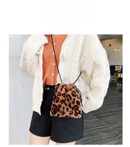 Model wearing a stylish leopard print faux fur bucket bag with drawstring closure