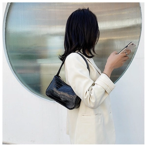 Photo street style d'un sac baguette noir à motif crocodile porté avec un tailleur chic