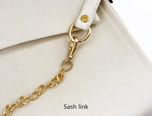 Detalle de mosquetón y anillo en D en bolso de lona beige con correa de cadena
